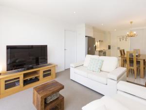 a living room with a white couch and a flat screen tv at The Edge Apartment 5 Jindabyne in Jindabyne