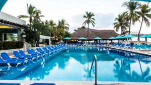una piscina con sillas azules y palmeras en Fontan Ixtapa, en Ixtapa