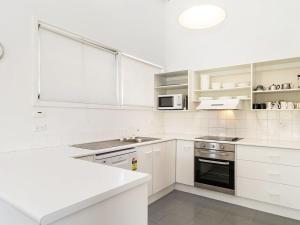 a white kitchen with a sink and a microwave at Matilda Spacious centrally located with great lake views in Jindabyne