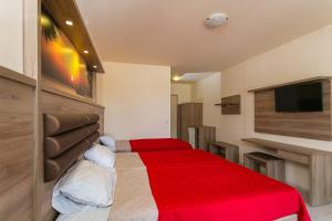 a bedroom with a bed with a red blanket at SunBay Hotel in Hersonissos