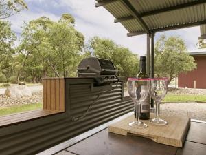 einen Grill mit einer Flasche Wein und zwei Gläsern in der Unterkunft Kickenback Studio Contemporary accommodation in the heart of Crackenback in Crackenback