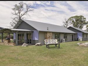 a house with a bench in the yard at Kickenback Studio Contemporary accommodation in the heart of Crackenback in Crackenback