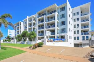 a large white apartment building with palm trees at The Point Resort in Bargara
