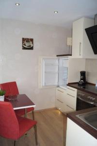 a small kitchen with a table and a red chair at Komfortappartement Robbe in Neuharlingersiel