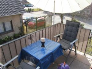 a table and a chair on a balcony with an umbrella at Komfortappartement Robbe in Neuharlingersiel