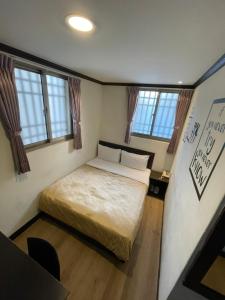 a small bedroom with a bed and windows at Holiday Business Hotel in Taitung City