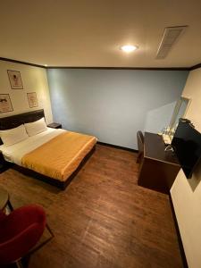 a bedroom with a bed and a chair and a table at Holiday Business Hotel in Taitung City