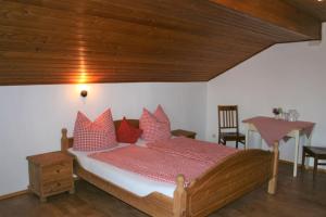 a bedroom with a bed with red pillows and a table at Beim Heiß'n in Staudach-Egerndach