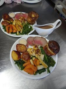 two plates of food with meat and vegetables on a table at Castle Inn in Hythe