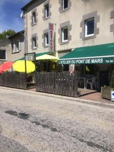 a building with a fence and umbrellas on a street at L'Atelier du Pont de Mars in Mars