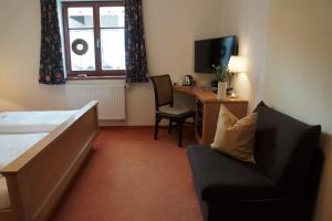 a bedroom with a bed and a desk and a chair at Pension Kramerhof in Taufkirchen