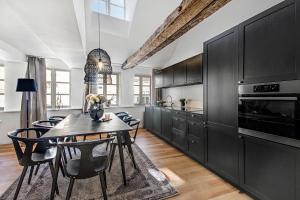 a kitchen with black cabinets and a table with chairs at Sanders Regent - Smart Two-Bedroom Apartment Near Central Square in Copenhagen
