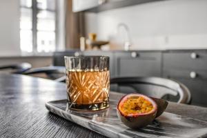 a glass of orange juice sitting on a table with a passion fruit at Sanders Regent - Smart Two-Bedroom Apartment Near Central Square in Copenhagen