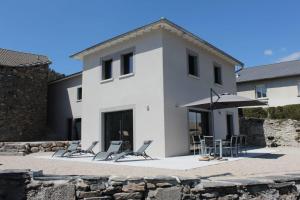 een wit huis met stoelen en een parasol bij L'AYMERAUDE in Messinhac