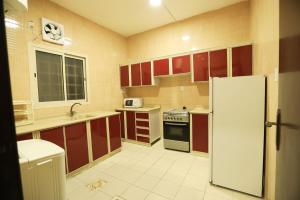 cocina con armarios rojos y nevera blanca en العييري للشقق المخدومة الدمام Al Eairy Serviced Apartments Dammam 7, en Dammam