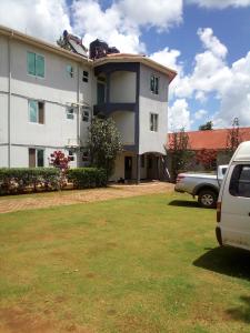 GuluDich Comfort Hotel University Branch的一栋白色建筑，前面停着一辆汽车