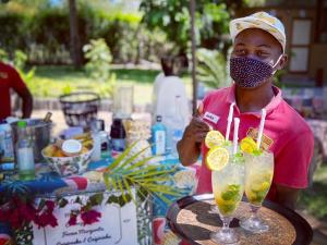 a man wearing a mask holding a tray of drinks at Mozambeat Motel in Praia do Tofo