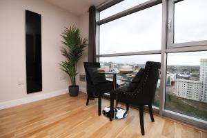 a dining room with a table and chairs and large windows at The View - LONG STAY OFFER - Modern Central Apartment and Parking by CTO Serviced Apartments in Cardiff