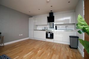 a kitchen with white cabinets and a wooden floor at The View - LONG STAY OFFER - Modern Central Apartment and Parking by CTO Serviced Apartments in Cardiff