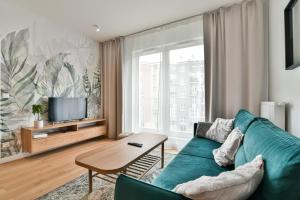 a living room with a green couch and a tv at LTC - Apartments Abrahama Śródmieście in Gdynia