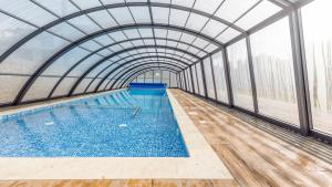 an indoor swimming pool with a glass ceiling at Apartamenty Sun & Snow Baltic Sun in Sztutowo