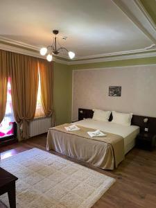 a bedroom with a large bed and two windows at BULGARI melnik in Melnik