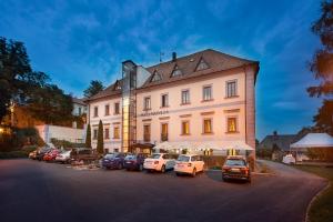 un grande edificio bianco con auto parcheggiate in un parcheggio di Maxmilian Lifestyle Resort a Loučeň