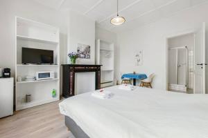 um quarto branco com uma cama grande e uma televisão em Romy&Travis - The Boulevard House in the Historic Centre em Bruges