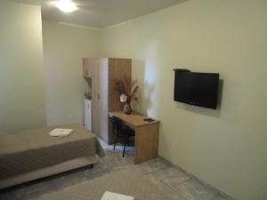 Habitación con cama, escritorio y TV. en HF Minas Hotel, en Vespasiano