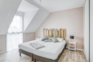 una camera da letto con un grande letto in una stanza bianca di L'Exploratrice a Saint-Lunaire