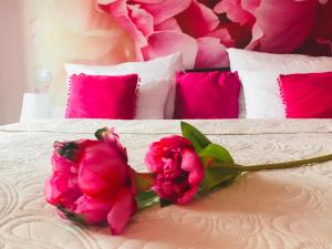 2 rosa Blumen auf einem Bett mit rosa Kissen in der Unterkunft Design Hotel Romantick in Třeboň