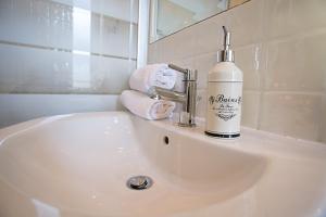 - un lavabo blanc dans la salle de bains avec une bouteille de savon dans l'établissement Colosseo Apartments and Rooms - Rome City Centre, à Rome