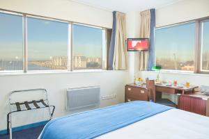 ein Schlafzimmer mit einem Bett, einem Schreibtisch und Fenstern in der Unterkunft Hôtel Les Gens De Mer Dunkerque by Popinns in Dunkerque