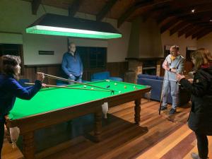 a group of people standing around a pool table at Hidden Haven Barrington Tops in Cobark