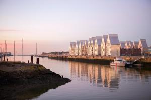 un bateau est amarré à côté d'un quai avec des bâtiments dans l'établissement Hôtel Les Gens De Mer Dunkerque by Popinns, à Dunkerque