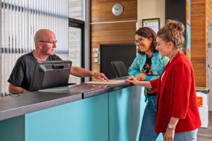 a man and two women standing at a reception desk at Stayokay Hostel Haarlem in Haarlem