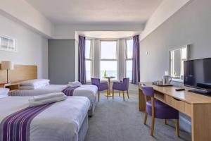 a hotel room with two beds and a desk and a television at The Beresford Hotel in Newquay