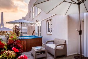 um pátio com uma banheira de hidromassagem, uma cadeira e um guarda-sol em Olive Arena Boutique&Business Hotel-By Ran Hotels em Nahariya