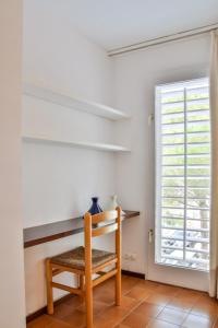 een kamer met een houten stoel en een raam bij CENTRIC APARTMENT CADAQUES -private parking - CA L'ELLA in Cadaqués