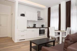 a kitchen with white cabinets and a table in a living room at Boardinghouse Rosenstraße in Hamburg