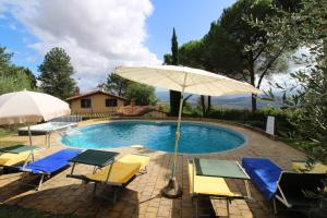 a pool with chairs and umbrellas next to a house at Villino Alba in Pieve a Maiano
