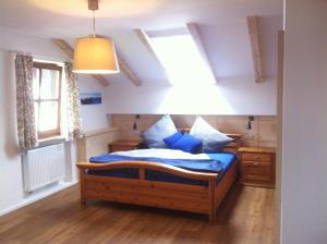 Schlafzimmer mit einem Bett mit blauer Bettwäsche und einem Fenster in der Unterkunft Ferienwohnung AmmerZonas & AmmerZone in Oberammergau