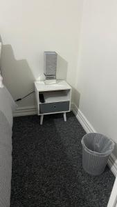 ein weißes Zimmer mit einem Bett und einer Kommode mit einem Radio in der Unterkunft bvapartments-Blackhouse in Huddersfield