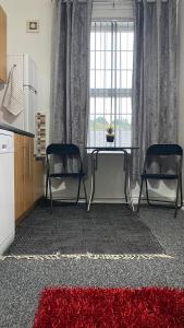 sala de estar con 2 sillas, mesa y alfombra roja en bvapartments-Blackhouse en Huddersfield