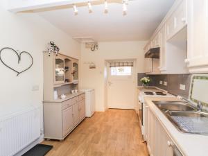 a kitchen with white cabinets and a wooden floor at Manor House Farm Cottage in Saltburn-by-the-Sea