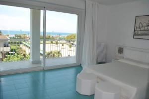 una camera bianca con una grande finestra e un letto di Elegante Attico panoramico a 2 passi dal mare a Forte dei Marmi