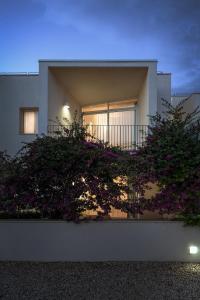 ein Haus mit einem Balkon mit lila Blumen in der Unterkunft Cala Palme Lampedusa in Lampedusa