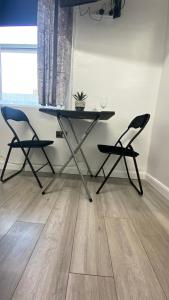 een tafel en 2 stoelen in een kamer met een houten vloer bij bvapartments-Queensgate 2 in Huddersfield