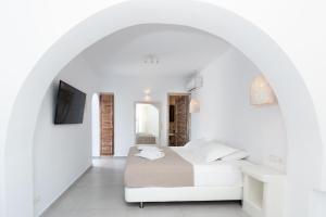 ein weißes Schlafzimmer mit einem Bett in einem Torbogen in der Unterkunft Naxos Sandastic in Agios Prokopios
