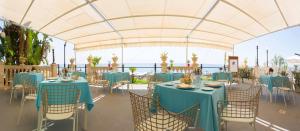 a tent with blue tables and chairs and the ocean at Hellenia Yachting Hotel & SPA in Giardini Naxos